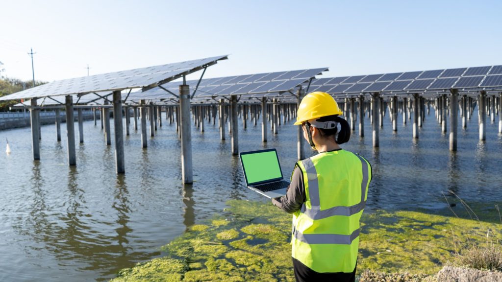 Back view of female engineer using laptop at solar power plant